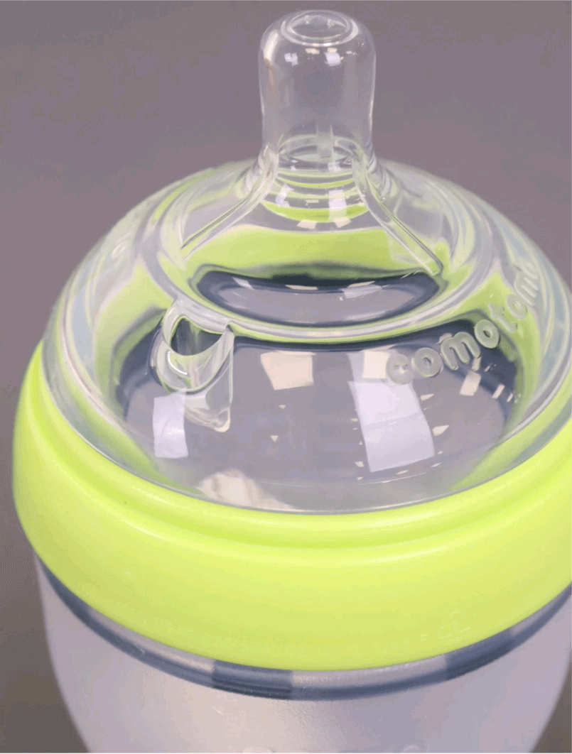 Baby bottle with green rim and clear nipple on a dark background, Comotomo baby bottle double pack