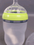 Silicone baby bottle with green rim and 'comotomo' branding on a gray background. Comotomo baby bottle double pack