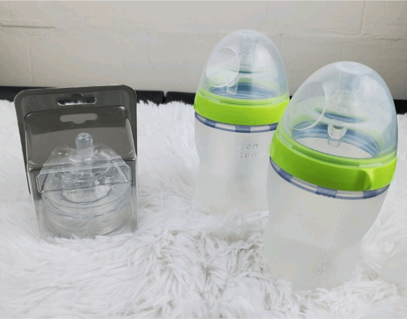 Silicone baby bottle with green rim and 'comotomo' branding on a gray background. Comotomo baby bottle double pack