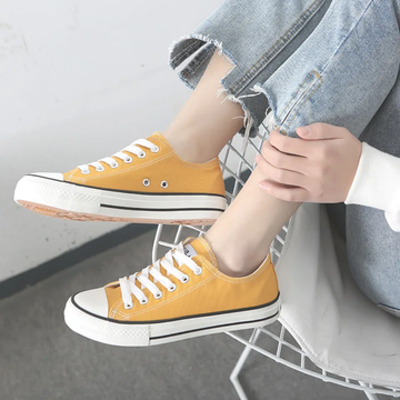 Person wearing yellow sneakers with white laces on a gray floor.