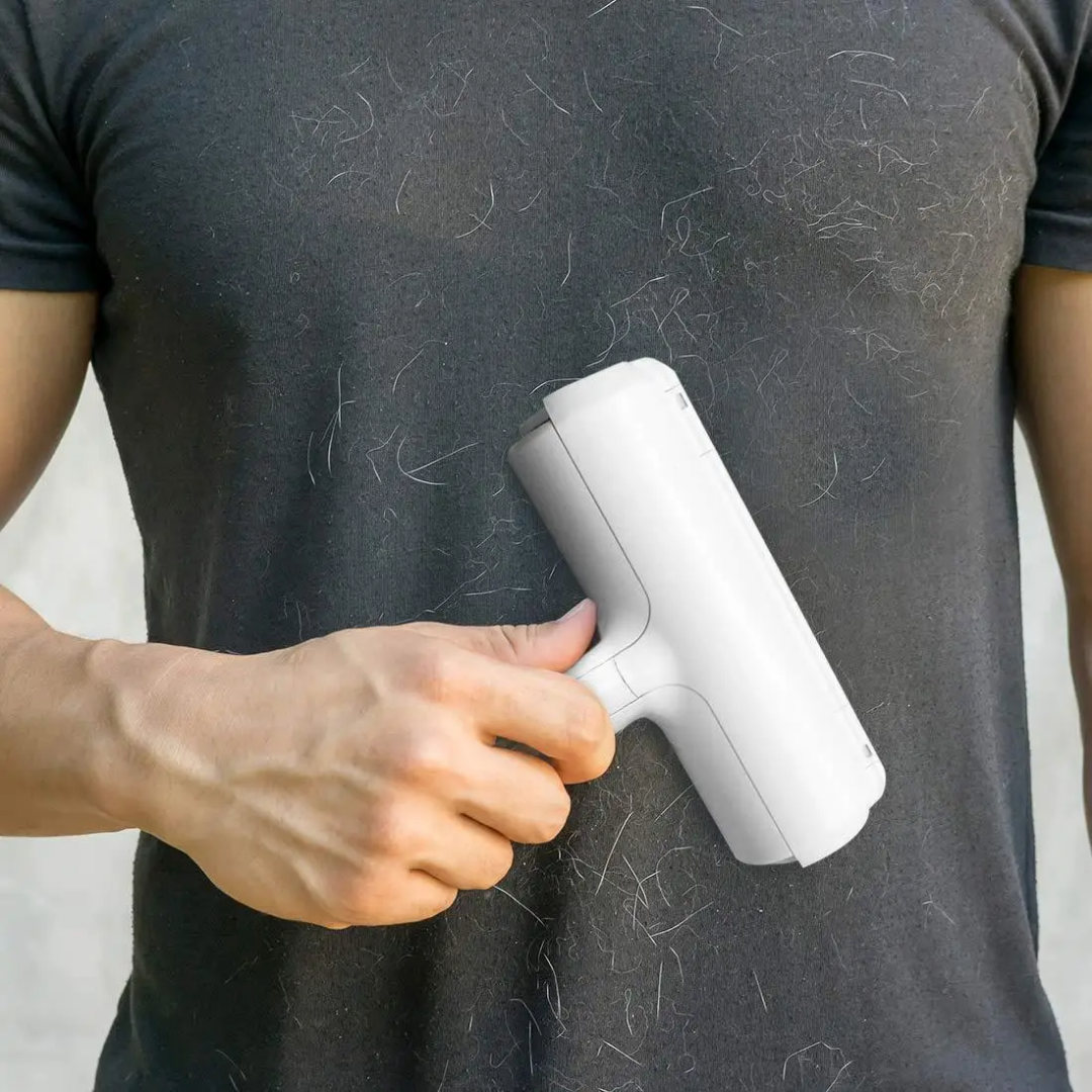 Person using a white hair removal device on a dark shirt with visible hair. Chum Chum Pet Hair Remover Roller